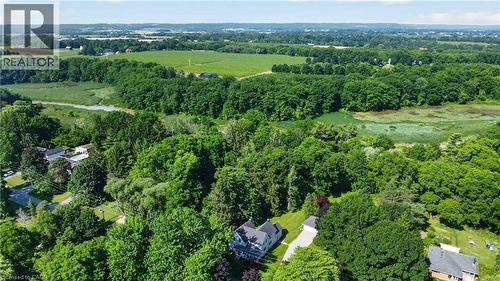 Aerial perspective showcasing a residential area enveloped by extensive green spaces, mature trees, and agricultural fields - 1629 Gregory Road, St. Catharines, ON 
