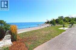 Expansive waterfront setting featuring a natural beach, clear blue water, and a paved pathway - 