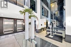 Lobby entrance featuring dual stainless steel elevators, large-format tile flooring, and a mirrored accent wall - 