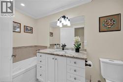 Bathroom featuring a white vanity with a granite countertop, undermount sink, and dark-finish hardware - 