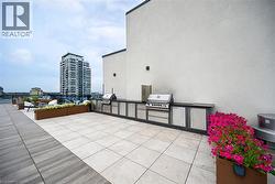 Expansive rooftop patio featuring an outdoor kitchen with built-in grills, integrated cabinetry, and stone countertops - 