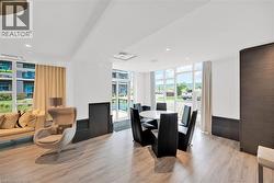 Bright, open common area featuring extensive window panels, light wood-finish flooring, recessed lighting, and a dark accent wall with integrated cabinetry - 