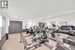 Fitness center featuring recessed lighting, a mirrored wall, and a selection of cardio equipment - 