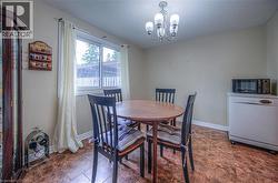 Dining area featuring a frosted glass chandelier, a large window, neutral wall tones, durable patterned flooring, and a built-in dishwasher - 