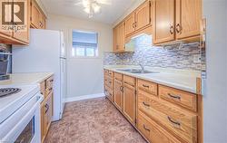 Galley kitchen featuring wood cabinetry, laminate countertops, a tile backsplash, and a double basin sink - 