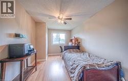 Room featuring wood-finish flooring, a window offering natural light, and a ceiling fan with integrated lighting - 