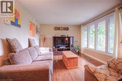 Living area with wood-finish flooring, a large multi-pane window, neutral wall paint, and a wall cutout - 