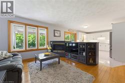 Living area featuring wood-finish flooring, a built-in entertainment unit with shelving, and a wall-mounted fireplace - 