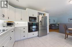 Kitchen with white cabinetry, stainless steel appliances, and light-toned tile flooring - 