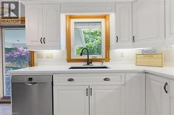 Kitchen workspace featuring white cabinetry, light-toned countertops, and a stainless steel dishwasher - 