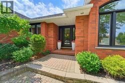 Brick facade exterior featuring a paver walkway, well-maintained landscaping, black-framed windows, and an arched transom window - 