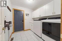 Laundry area featuring white cabinetry, a built-in sink, and tile flooring - 