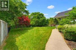 Expansive green lawn with mature trees, including a vibrant red-leafed specimen - 