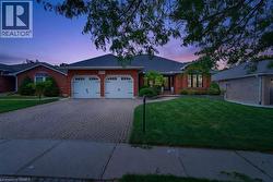 Brick exterior residence featuring a patterned paver driveway, an attached two-car garage, and a manicured front lawn - 
