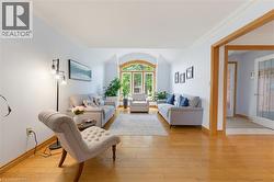 Living area featuring wood-finish flooring, a large arched window, crown molding, and light wall tones - 