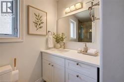 Bathroom featuring a white vanity with shaker-style cabinetry, a built-in sink, and a large mirror - 