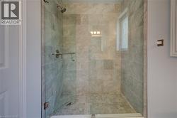 Frameless glass shower enclosure featuring large format stone-finish wall tile and mosaic tile flooring - 