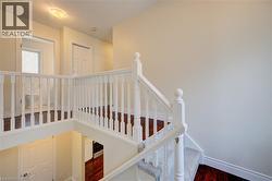 Upper-level hallway featuring a white baluster railing and wood-finish flooring - 