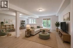 Open-concept lower level with light wood-finish flooring, white walls, and recessed lighting - 