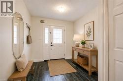 Foyer entrance featuring dark wood-finish flooring, a white paneled door with glass inserts, and light-toned walls - 