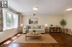 Spacious living area featuring large windows, wood-finish flooring, recessed ceiling lights, and light-toned wall finishes - 