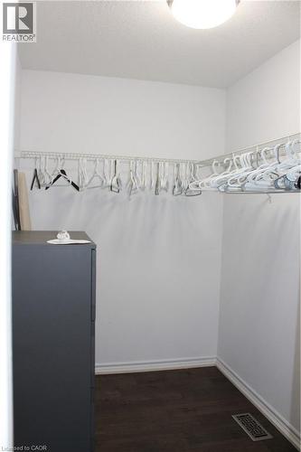 Walk-in closet featuring wood-finish flooring, white baseboards, and a built-in wire shelving system - 27 Stillwater Street, Kitchener, ON 