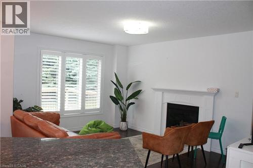 Living space featuring dark wood-finish flooring, white walls, and a recessed fireplace with a white mantel - 27 Stillwater Street, Kitchener, ON 