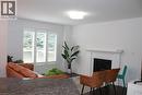 Living space featuring dark wood-finish flooring, white walls, and a recessed fireplace with a white mantel - 27 Stillwater Street, Kitchener, ON 