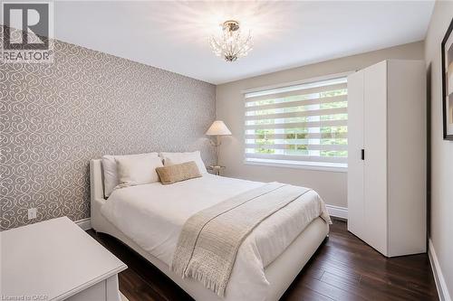 Bedroom featuring dark wood-finish flooring, a decorative accent wall, and a crystal chandelier - 355 Edgehill Drive, Kitchener, ON 