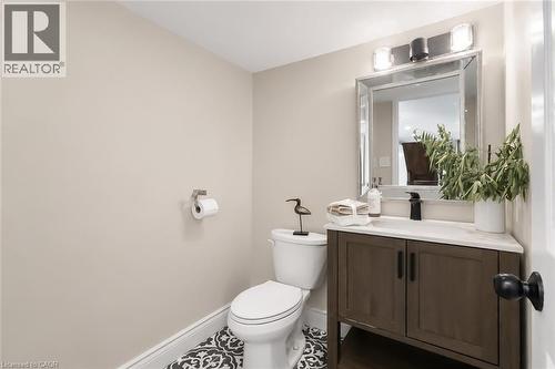 Powder room featuring a dark wood-finish vanity with a light countertop, a framed mirror, and decorative patterned floor tiles - 355 Edgehill Drive, Kitchener, ON 