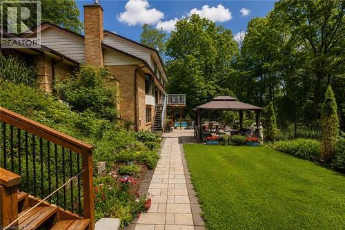 Expansive backyard featuring a manicured lawn, a stone paver pathway, and mature trees - 355 Edgehill Drive, Kitchener, ON 