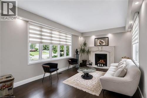 Living space featuring a prominent fireplace with a detailed mantel, dark wood-finish flooring, recessed lighting, expansive windows with custom blinds, and painted walls - 355 Edgehill Drive, Kitchener, ON 