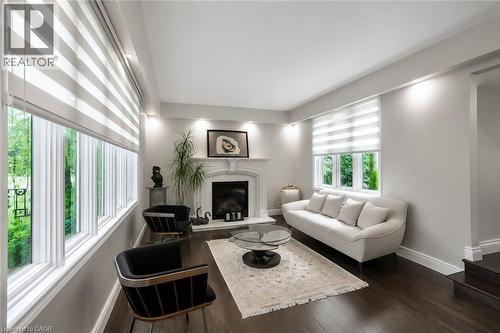 Spacious living area featuring dark wood-finish flooring, a white fireplace with ornate mantel, recessed lighting, and multiple windows with striped roller blinds - 355 Edgehill Drive, Kitchener, ON 