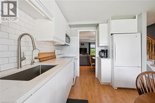 Kitchen featuring white flat-panel cabinetry, white subway tile backsplash, white countertops, and wood-finish flooring - 315 Mayview Crescent Unit# B, Waterloo, ON 