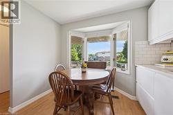 Bright dining area featuring a bay window, light wood-finish flooring, and white baseboards - 
