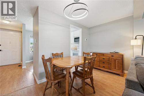 Dining area featuring wood-finish flooring, a contemporary circular chandelier, and a built-in wooden sideboard - 315 Mayview Crescent Unit# B, Waterloo, ON 