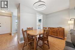 Dining area featuring wood-finish flooring, a contemporary circular chandelier, and a built-in wooden sideboard - 