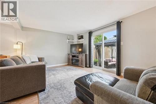 Living area with light wood-finish flooring, light gray wall color, and a sliding glass door leading to an outdoor patio with a pergola - 315 Mayview Crescent Unit# B, Waterloo, ON 