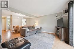 Spacious living area featuring light wood-finish flooring, light gray wall tones, and a large window with vertical blinds - 