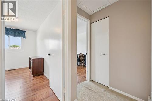 Hallway featuring light beige walls and carpeting, with white doors and black hardware - 315 Mayview Crescent Unit# B, Waterloo, ON 