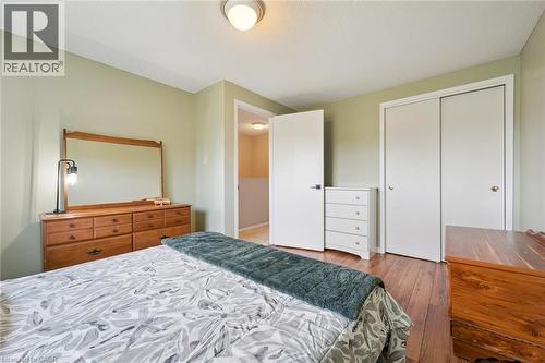 Bedroom featuring hardwood flooring, a ceiling-mounted light fixture, and two white sliding closet doors - 315 Mayview Crescent Unit# B, Waterloo, ON 