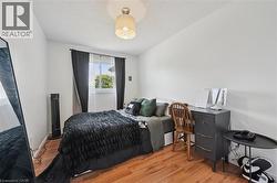 Bedroom with wood-finish flooring, a window featuring white trim, and a ceiling light fixture - 