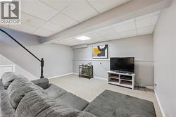 Finished recreational space featuring neutral wall tones, drop-panel ceiling, and light-toned carpet - 