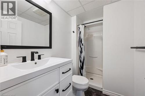 Bathroom featuring a white vanity with matte black hardware, a rectangular mirror, a white undermount sink with a matte black faucet, a white shower stall, and dark wood-finish flooring - 315 Mayview Crescent Unit# B, Waterloo, ON 