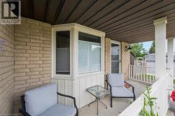 Covered porch featuring a brick exterior and a bay window with white trim - 