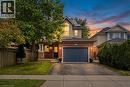 Brick and siding exterior featuring an attached garage with a paneled door, a covered front entry, and a paved driveway - 128 Houghton Street, Cambridge, ON 
