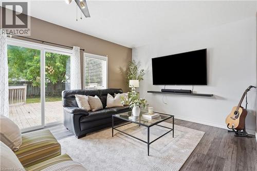 Spacious living area featuring wood-finish flooring, a ceiling fan, and a built-in wall shelf - 128 Houghton Street, Cambridge, ON 