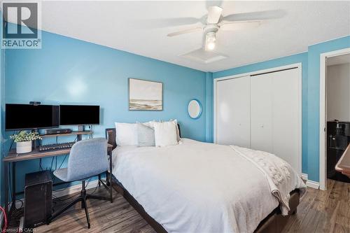 Bedroom featuring wood-finish flooring, a ceiling fan, and white bi-fold closet doors - 128 Houghton Street, Cambridge, ON 