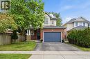 Two-story residence featuring brick and siding exterior, an integrated garage with a blue door, a partial stone facade, and a covered front entry with columns - 128 Houghton Street, Cambridge, ON 