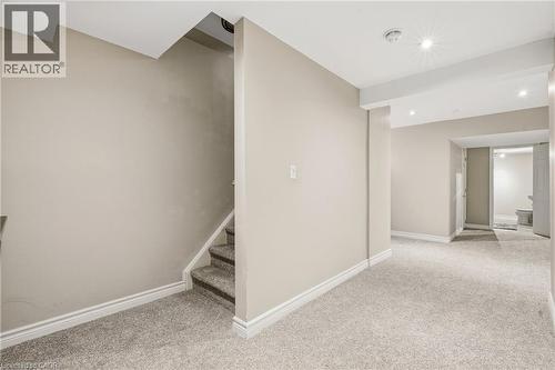 Recessed lighting illuminates a spacious carpeted area with neutral-toned walls and white baseboards - 128 Houghton Street, Cambridge, ON 